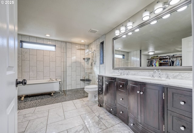 bathroom featuring a freestanding tub, visible vents, walk in shower, and a sink