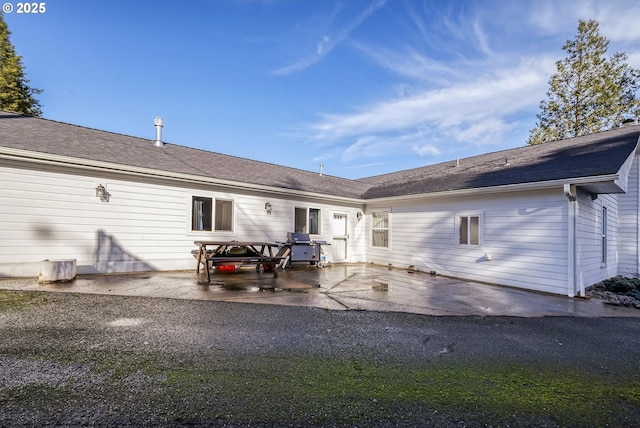 back of property featuring roof with shingles and a patio