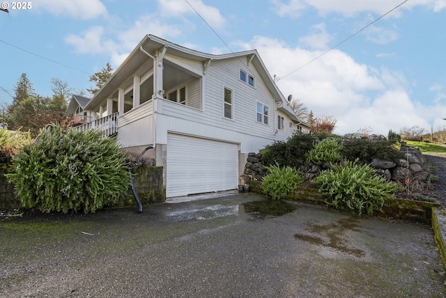 view of side of property featuring aphalt driveway and an attached garage