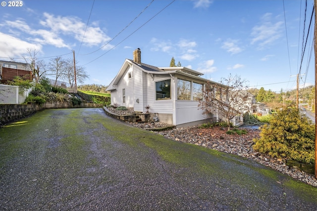 view of side of property featuring driveway and a chimney