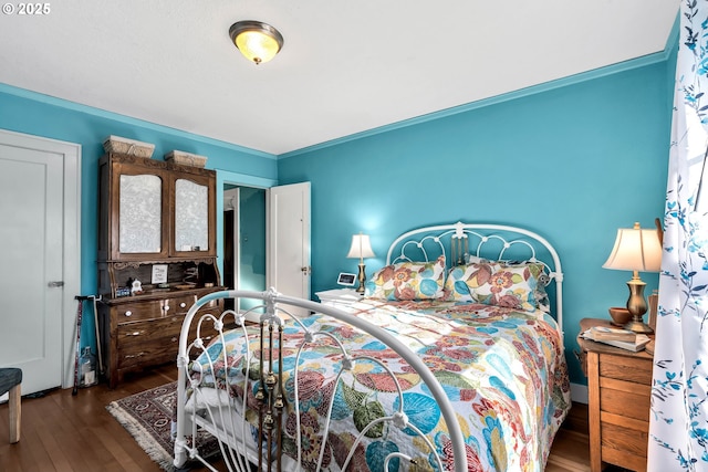 bedroom with ornamental molding and dark hardwood / wood-style floors