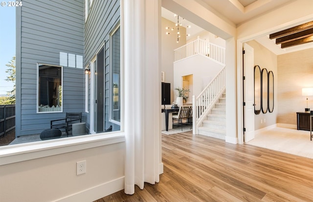 interior space with hardwood / wood-style flooring, beamed ceiling, a high ceiling, and an inviting chandelier