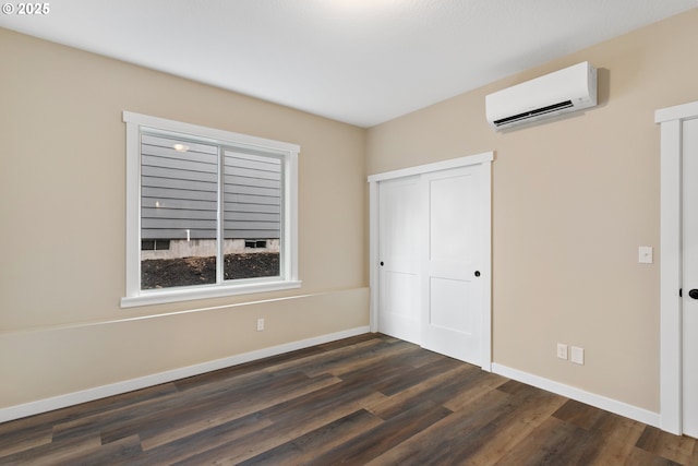 144 E H St, Vernonia, OR 97064 - unfurnished bedroom with a wall mounted AC, baseboards, dark wood-style floors, and a closet