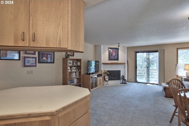 kitchen featuring a fireplace, carpet floors, a textured ceiling, and light brown cabinets