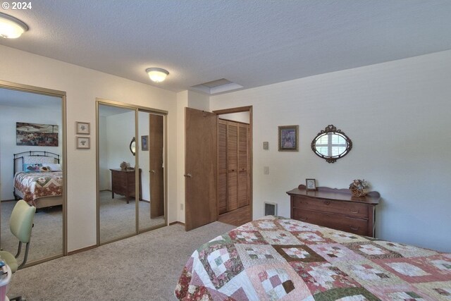 carpeted bedroom featuring a textured ceiling and multiple closets