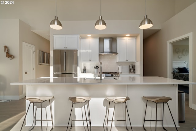 kitchen featuring wall chimney range hood, white cabinetry, stainless steel appliances, and a large island