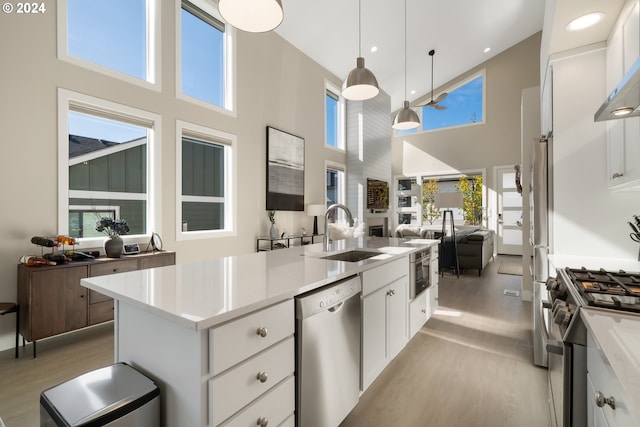 kitchen with a healthy amount of sunlight, appliances with stainless steel finishes, sink, white cabinetry, and a high ceiling