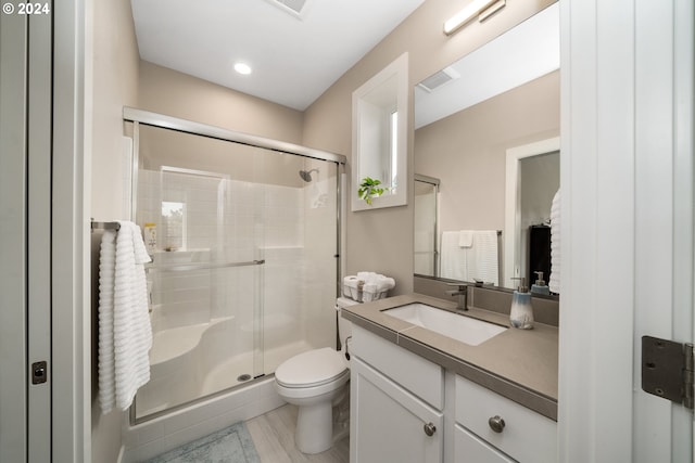 bathroom featuring vanity, toilet, wood-type flooring, and a shower with door