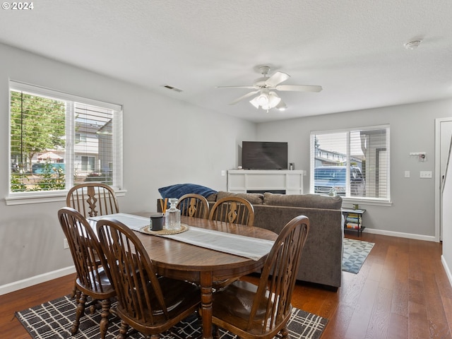 dining space featuring ceiling fan, a healthy amount of sunlight, dark hardwood / wood-style floors, and a textured ceiling