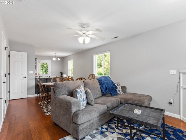 living room featuring ceiling fan with notable chandelier and dark hardwood / wood-style floors