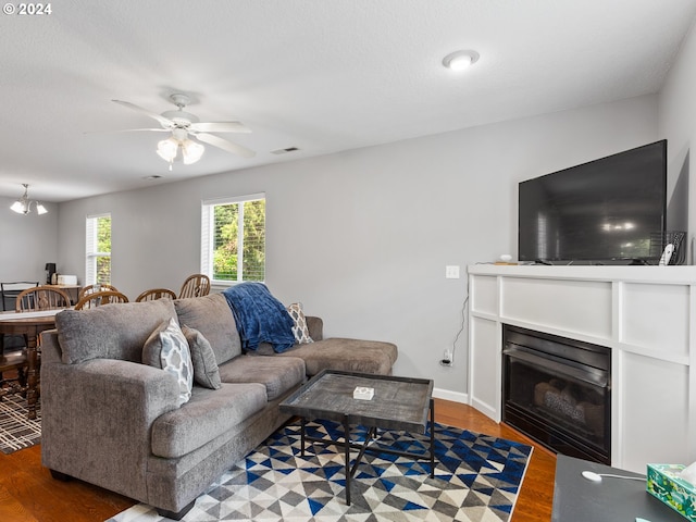 living room featuring ceiling fan with notable chandelier and wood-type flooring