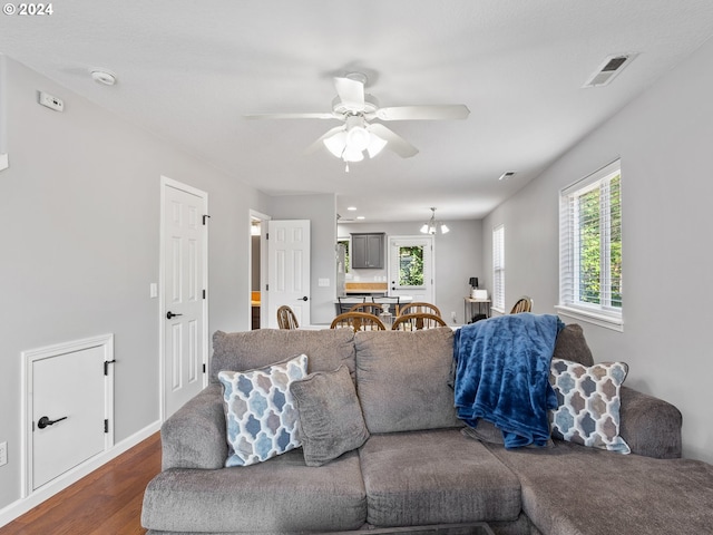 living room with dark hardwood / wood-style floors and ceiling fan with notable chandelier