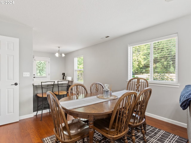 dining room with dark wood-type flooring and a notable chandelier