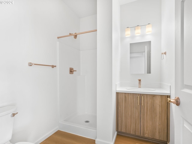 bathroom featuring vanity, a shower, hardwood / wood-style flooring, and toilet