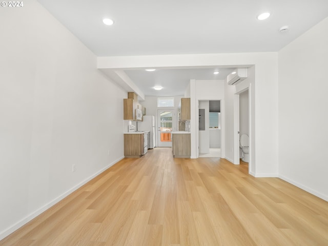 unfurnished living room with a wall mounted air conditioner and light hardwood / wood-style flooring