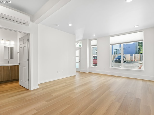 unfurnished living room with a wall unit AC and light wood-type flooring