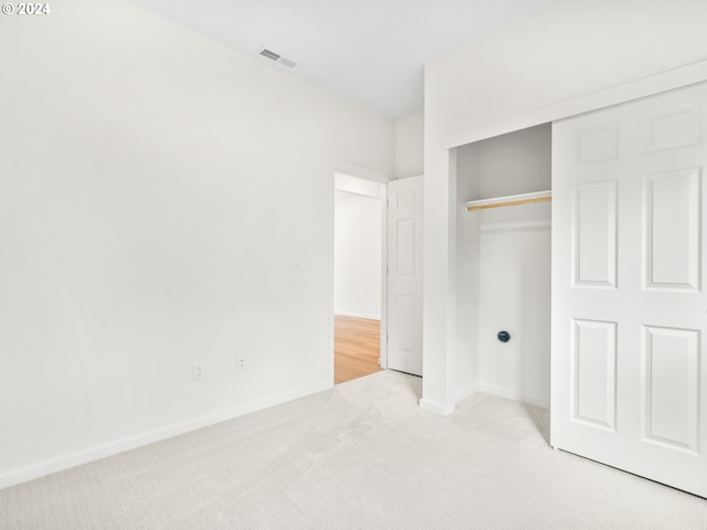 unfurnished bedroom with light carpet and a closet