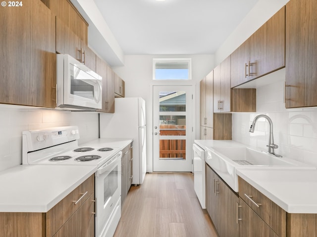 kitchen with white appliances, light hardwood / wood-style flooring, tasteful backsplash, and sink