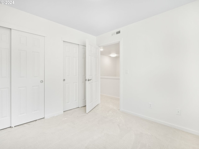 unfurnished bedroom with light carpet and multiple closets