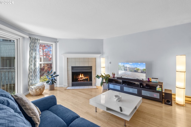 living room with a tile fireplace and light hardwood / wood-style floors