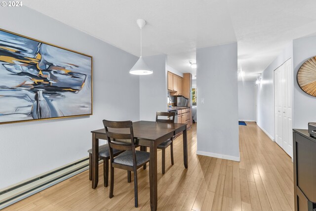 dining space featuring light wood-type flooring and a baseboard heating unit