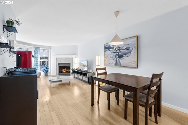 dining area with light wood-type flooring and a fireplace