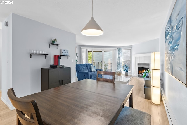 dining space with a fireplace and light hardwood / wood-style flooring