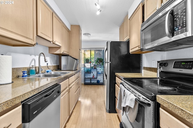 kitchen featuring sink, stainless steel appliances, light hardwood / wood-style flooring, a textured ceiling, and light brown cabinetry