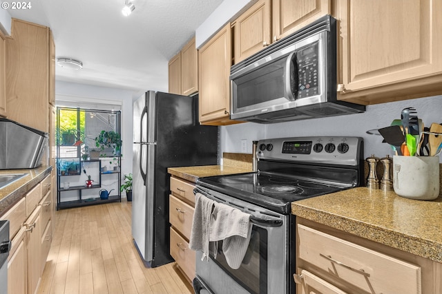 kitchen featuring light brown cabinets, light hardwood / wood-style floors, a textured ceiling, and appliances with stainless steel finishes