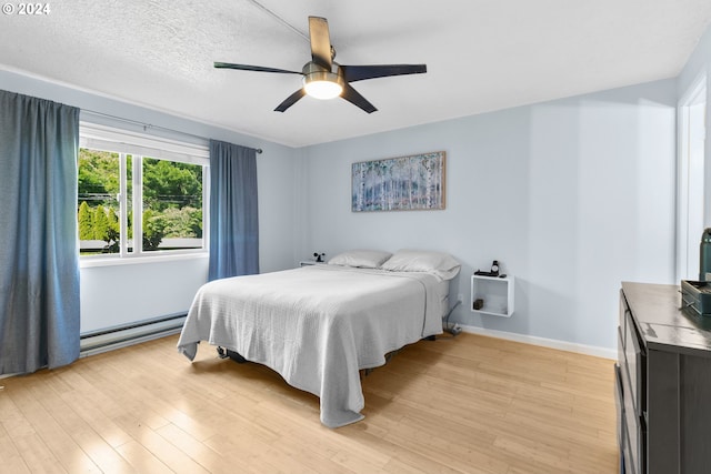 bedroom featuring ceiling fan, light hardwood / wood-style flooring, a textured ceiling, and a baseboard heating unit