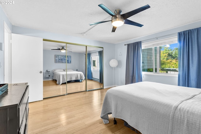 bedroom with ceiling fan, a closet, light hardwood / wood-style floors, and a textured ceiling