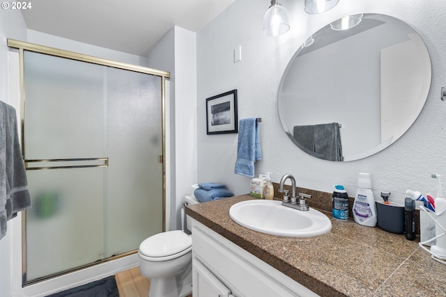 bathroom with hardwood / wood-style floors, vanity, toilet, and walk in shower