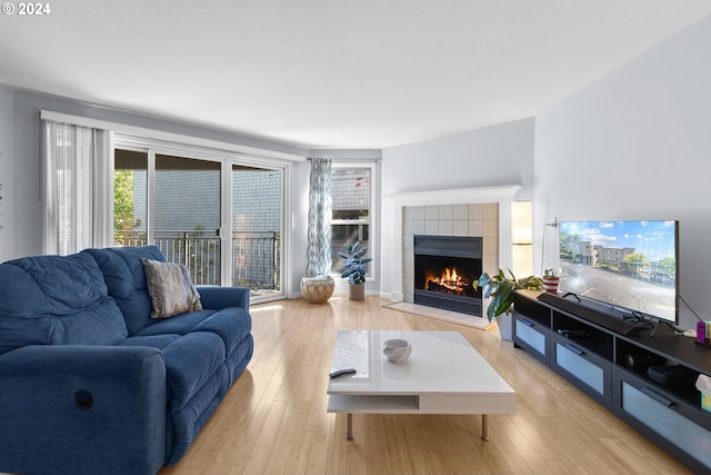 living room featuring a tile fireplace and light hardwood / wood-style floors