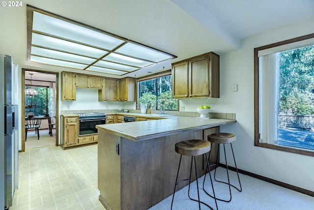 kitchen featuring a healthy amount of sunlight, stainless steel appliances, a kitchen breakfast bar, and kitchen peninsula