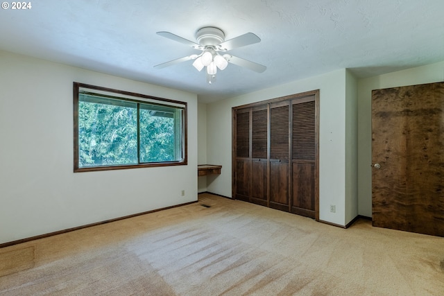 unfurnished bedroom featuring light carpet, ceiling fan, and a closet