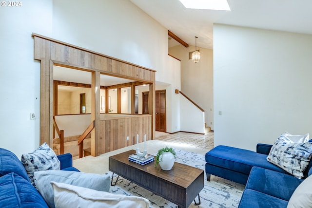 living room featuring a chandelier, a skylight, high vaulted ceiling, beamed ceiling, and light colored carpet