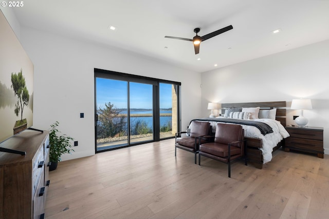 bedroom with recessed lighting, light wood-type flooring, a water view, and access to outside