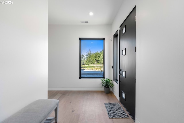 corridor with visible vents, baseboards, and light wood finished floors