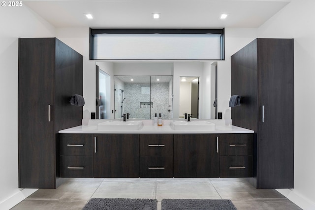 bathroom with double vanity, a stall shower, baseboards, and a sink