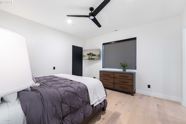 bedroom featuring visible vents, a ceiling fan, baseboards, and wood finished floors