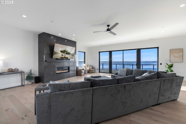 living room with recessed lighting, a ceiling fan, light wood-type flooring, and a large fireplace