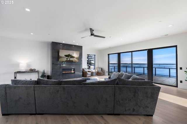 living room with visible vents, a large fireplace, a ceiling fan, and wood finished floors