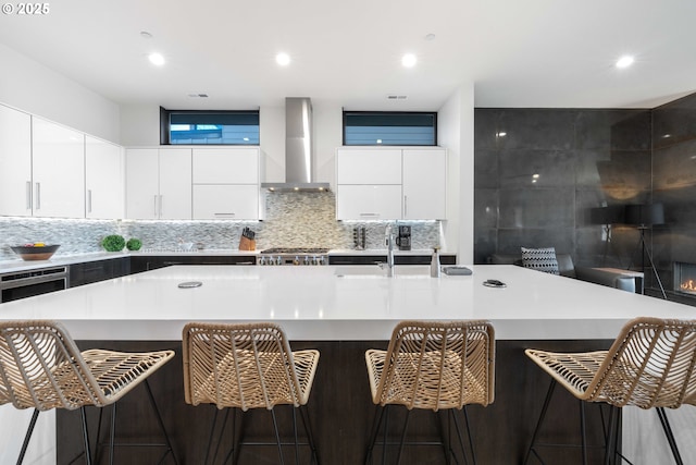 kitchen featuring a large island, modern cabinets, wall chimney exhaust hood, and a sink