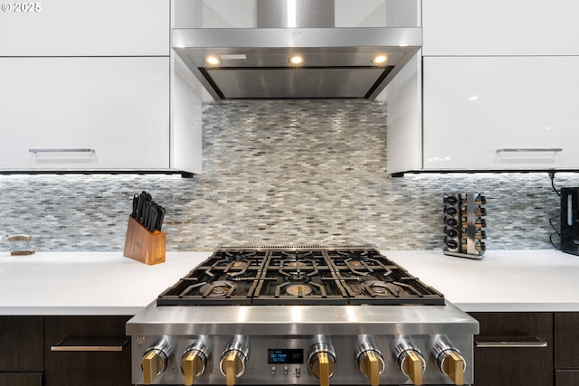 kitchen with modern cabinets, wall chimney range hood, tasteful backsplash, range with gas cooktop, and light countertops