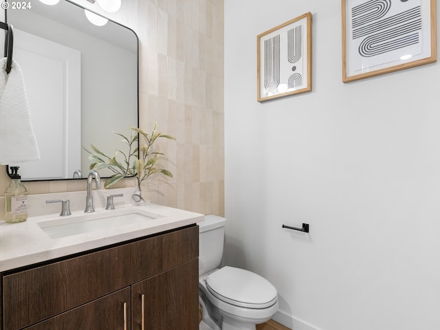 bathroom featuring vanity, toilet, and decorative backsplash