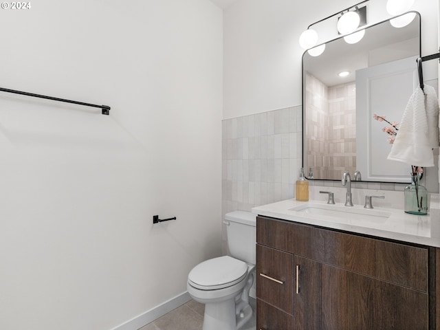 bathroom featuring toilet, vanity, tile patterned floors, and tile walls