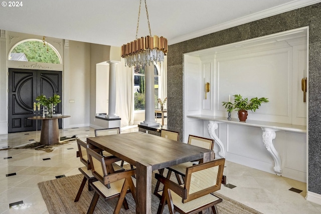 dining area with a notable chandelier, crown molding, and ornate columns