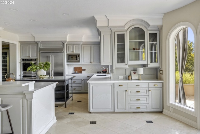 kitchen with gray cabinets, built in appliances, sink, and a healthy amount of sunlight