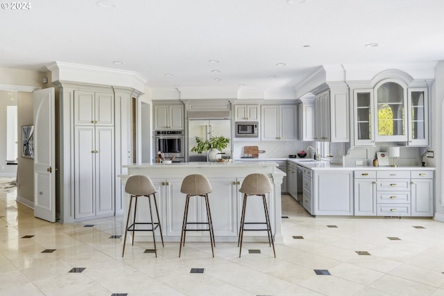 kitchen with gray cabinets, a kitchen breakfast bar, a center island, and built in appliances