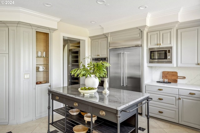 kitchen with ornamental molding, light tile patterned flooring, and built in appliances